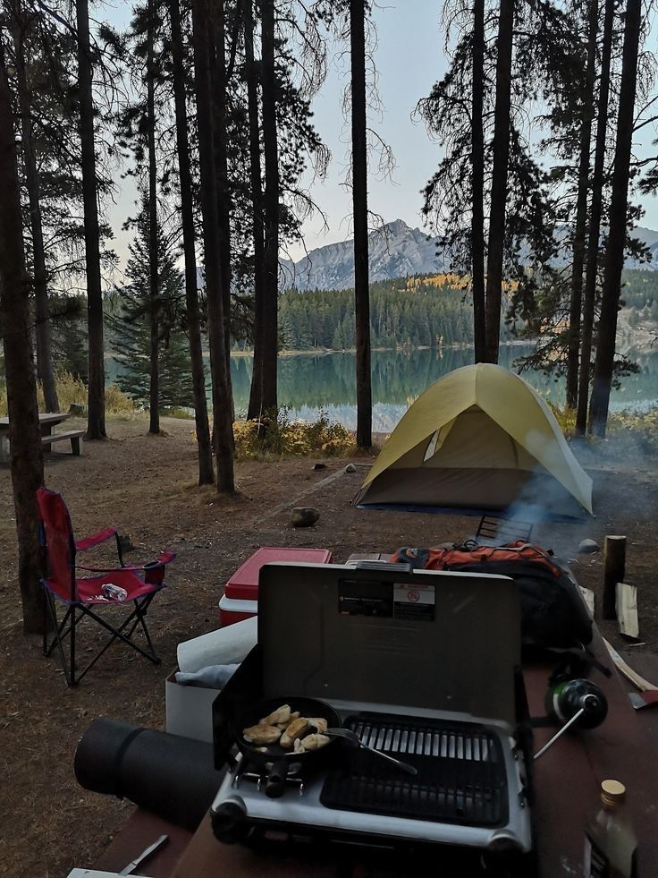 a camp site with a grill and tent in the background