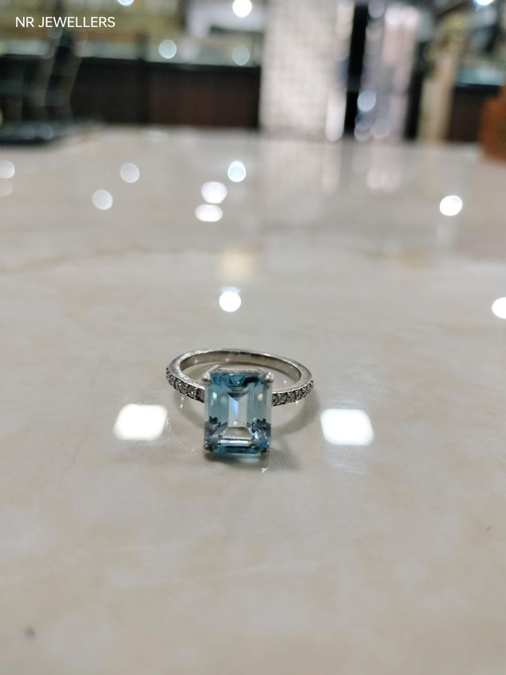 a ring with a blue topaz sits on a white countertop in a store