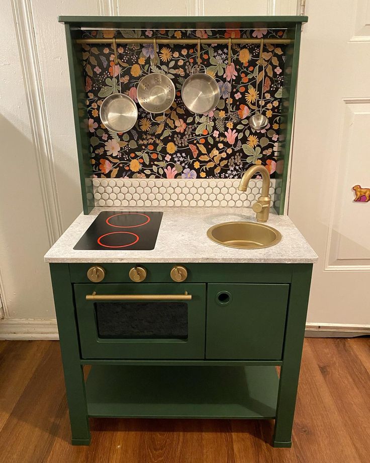 a green stove top oven sitting next to a wall with pots and pans on it