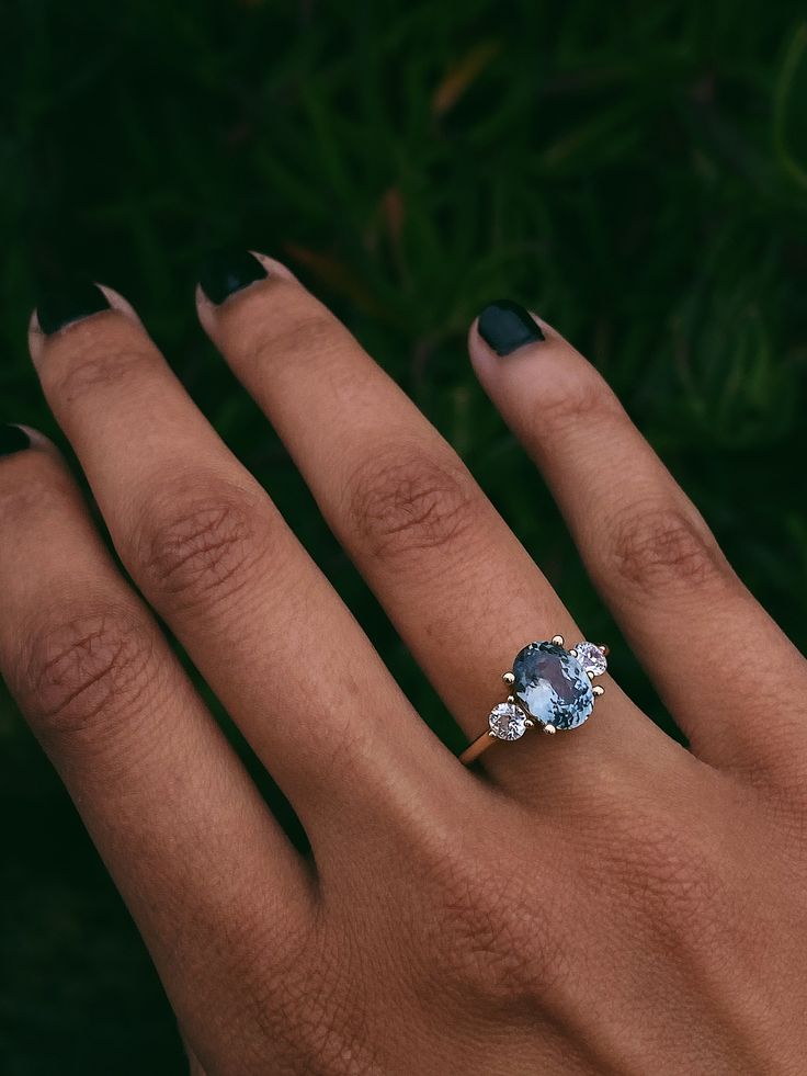 a woman's hand with a ring on top of her finger and an oval blue stone in the middle