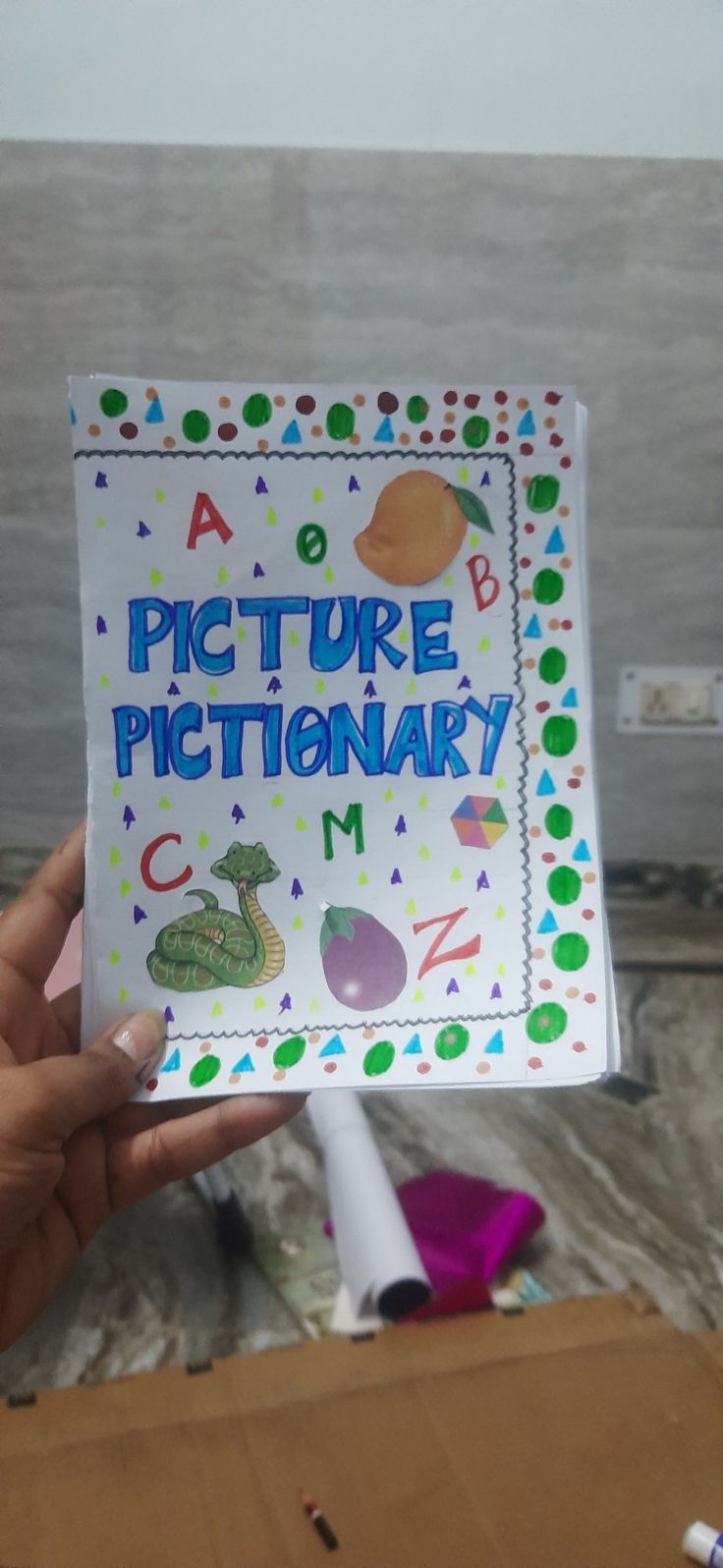 a person holding up a sign that says picture dictionary in front of the camera and an object behind it