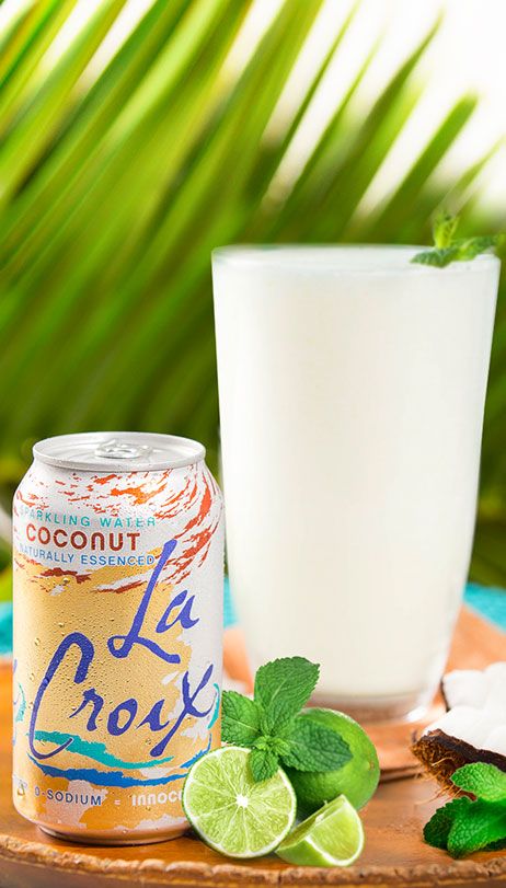 a can of coconut milk next to a glass of limeade on a wooden tray