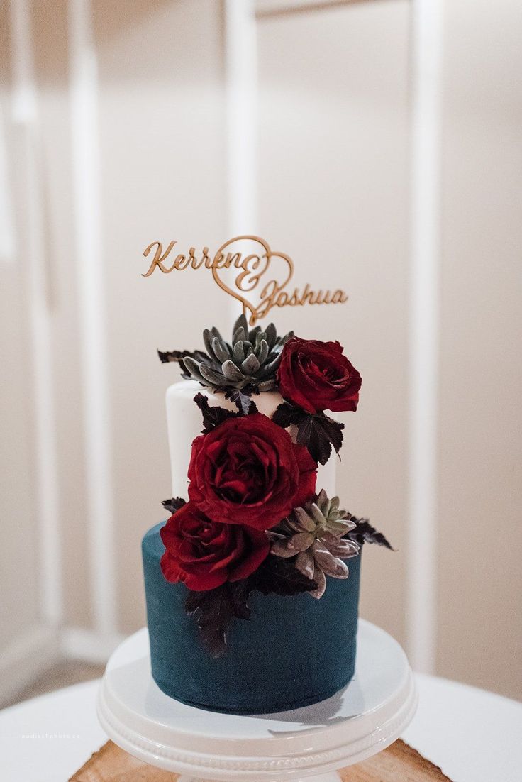 a blue and white cake with red roses on top