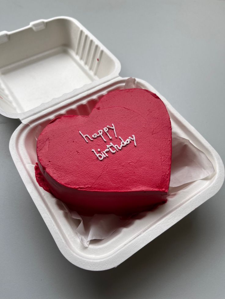 a red heart shaped cake in a foam container with the words happy birthday written on it