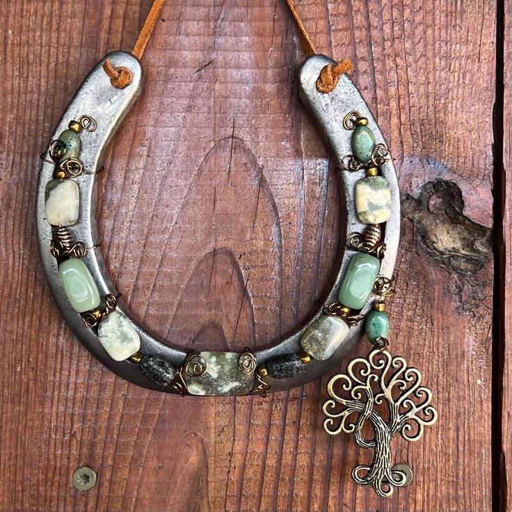 a necklace is hanging on a wooden door with a metal cross and bead accents