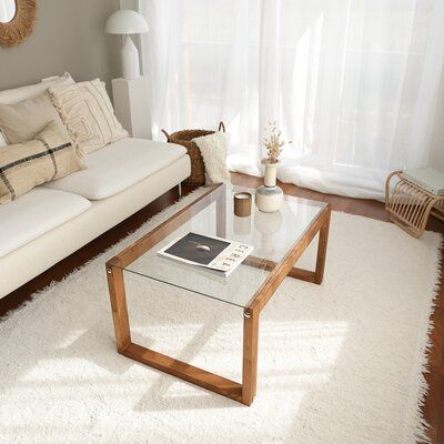 a living room with a couch, coffee table and rug in front of the window