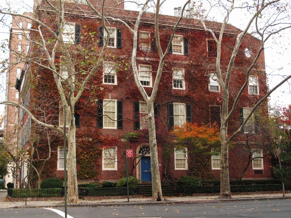 a red brick building with many windows and trees in front of it on a city street