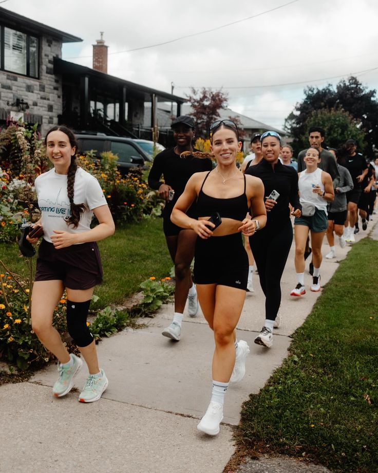 a group of people that are walking down a sidewalk together in shorts and tennis shoes