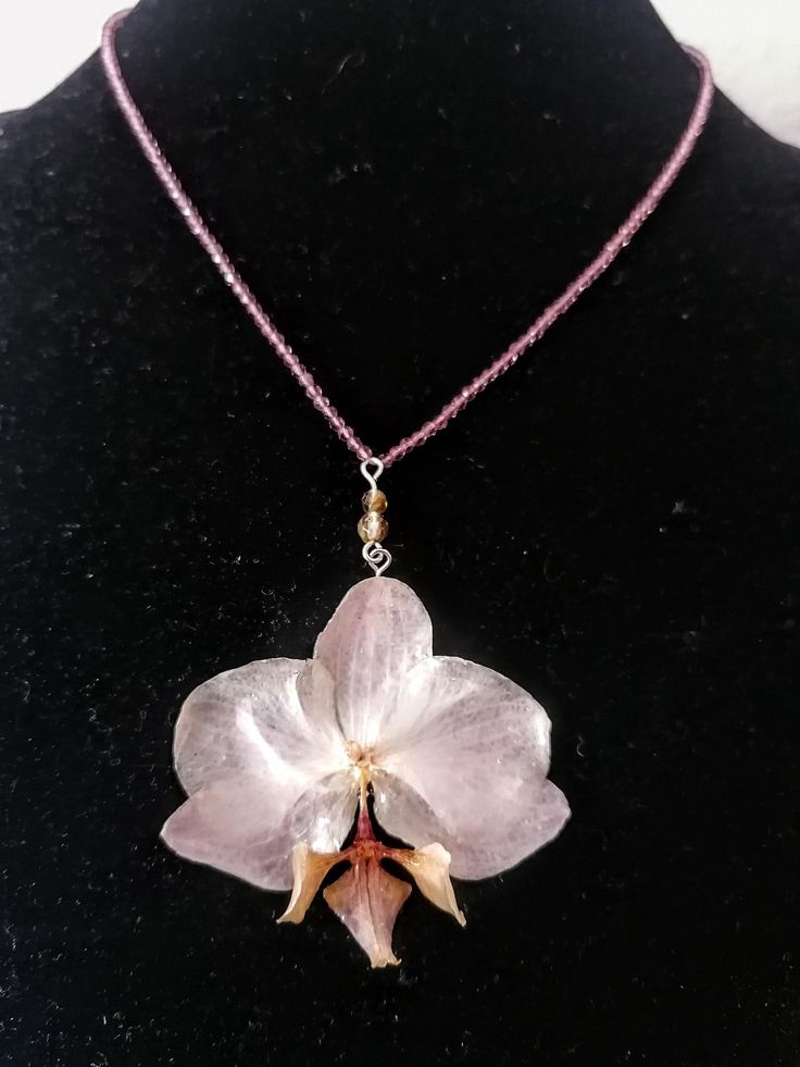 ☀️ Embrace the timeless beauty of orchids with this captivating handmade necklace! This exquisite necklace is more than just an accessory; it's a wearable work of art that captures the elegance and sophistication of orchids. Unlike traditional dried flowers, the orchid in this necklace is preserved in crystal-clear resin, ensuring its long-lasting beauty! Here's what makes this necklace special: Uniquely handcrafted: I cultivate and preserve the orchids myself, ensuring each necklace is a one-of-a-kind creation. You won't find another piece exactly like it! Timeless orchid design: The orchid's graceful silhouette and vibrant colors add a touch of sophistication and elegance to any outfit. Durable resin pendant: The crystal-clear resin encasing the orchid protects it from damage, ensuring y Etsy Necklaces Unique, Handmade Orchid Earrings, Real Orchid Jewelry, Unique Orchid-colored Jewelry Gift, Dried Flower Necklace, Orchid Necklace Silver, Orchid Pendant, Orchid Jewelry, Orchid Necklace