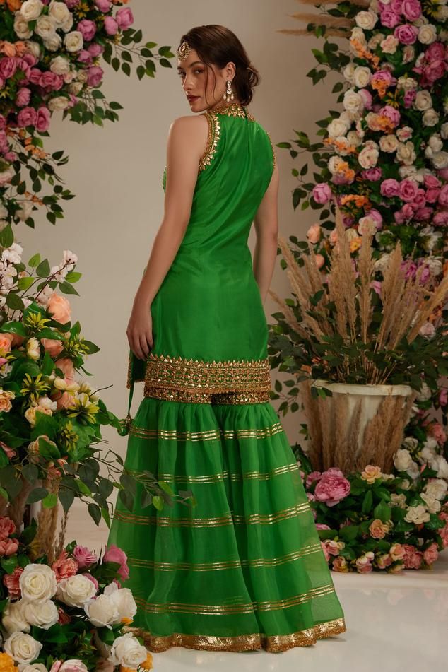 Green silk short kurta adorned with gota work in floral patterns, shimmering sequins, and delicate lace accents. Comes with gharara with intricate lacchi work, and a golden lace-trimmed organza dupatta.
Components: 3
Pattern: Embroidered
Type Of Work: Gota
Neckline: Round
Sleeve Type: Sleeveless
Fabric: Kurta and Gharara: Silk, Dupatta: Organza
Color: Green
Other Details: 
Fringed border dupatta
Closure: Gharara: Drawstring tie-up
Occasion: Wedding,Sangeet - Aza Fashions Golden Lace, Short Kurta, Gota Work, Floral Set, Organza Dupatta, Silk Dupatta, Silk Shorts, Green Silk, Embroidered Silk