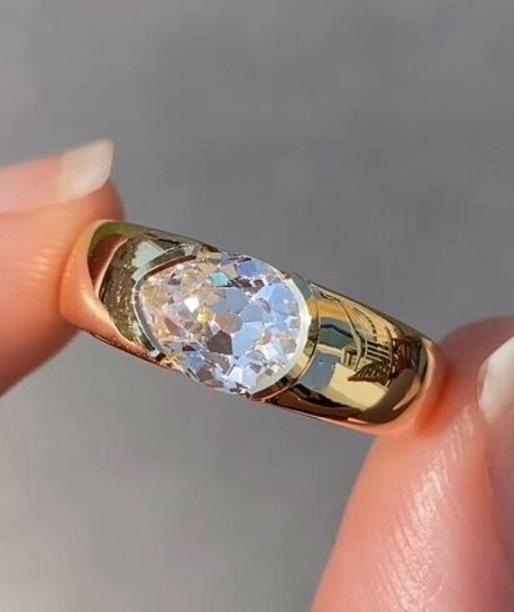 a close up of a person's hand holding a ring with a diamond in it