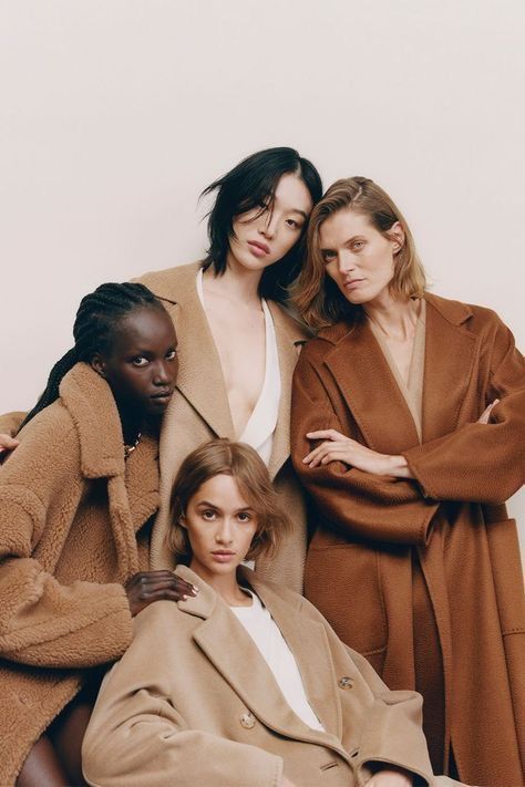 three models pose for the camera with their arms around each other, both wearing brown coats