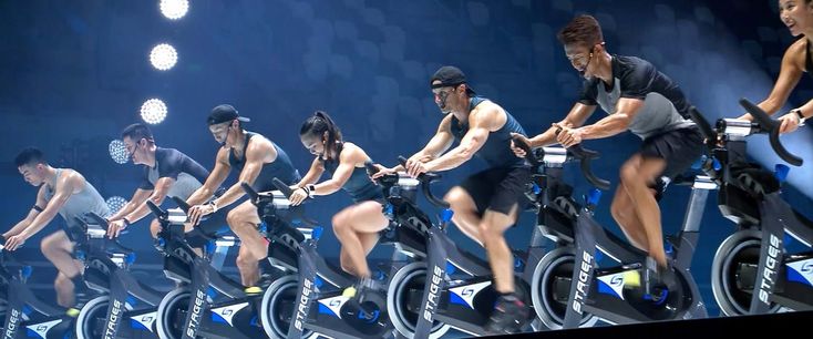 a group of people riding stationary bikes in a row