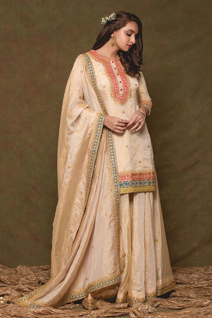 Light gold kurta with sequin embroidery. Paired with sharara and dupatta.
Component: 3
Pattern: Embroidery
Type Of Work: Sequin
Neckline: Round
Sleeve Type: Three quarter
Fabric: Pure Tissue
Color: Gold
Other Details: 
Front embellished buttons
Tassel bordered sheer dupatta
Occasion: Sangeet - Aza Fashions Chinon Sharara For Reception And Eid, Eid Reception Sharara In Chinon, Eid Reception Chinon Sharara, Reception Sharara With Dabka Work In Chinon, Chinon Sharara With Dabka Work For Reception, Unstitched Chinon Sharara For Reception, Raw Silk Palazzo Set With Zari Work For Reception, Resham Embroidery Chinon Palazzo Set For Reception, Reception Palazzo Set With Resham Embroidery In Chinon