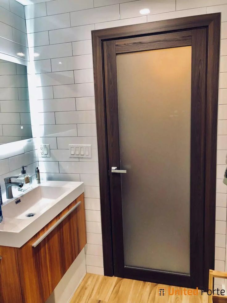 a bathroom with a sink, mirror and shower stall door in it's corner