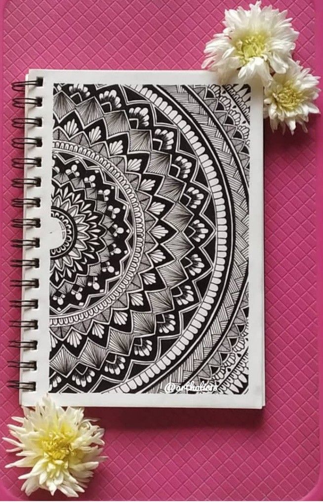 a spiral notebook with some flowers on the side and a pink background next to it