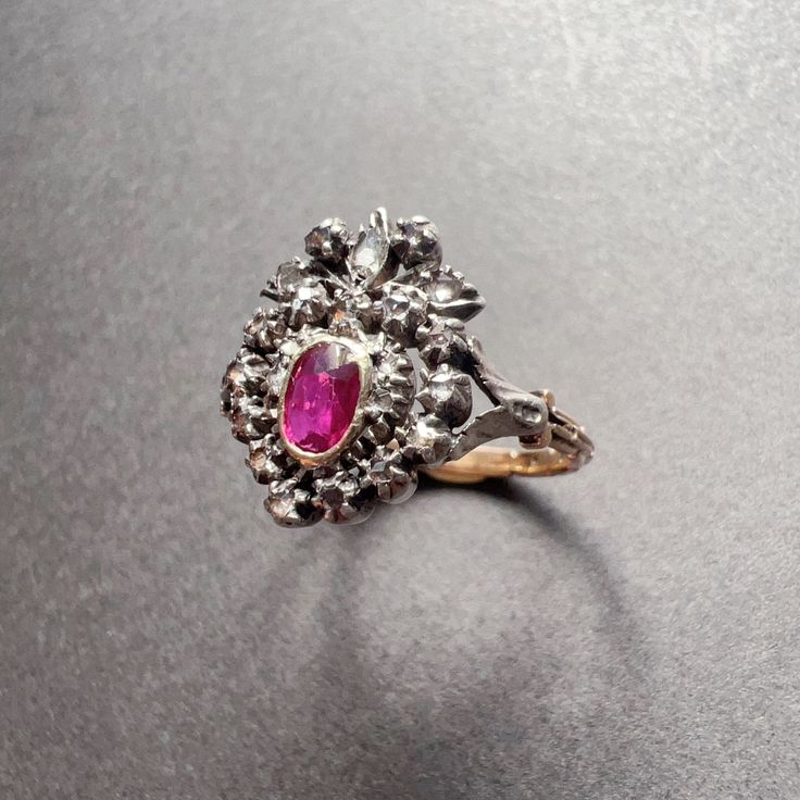 a close up of a ring with a pink stone in it on a gray surface