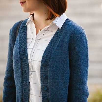 a woman wearing a blue cardigan and white shirt