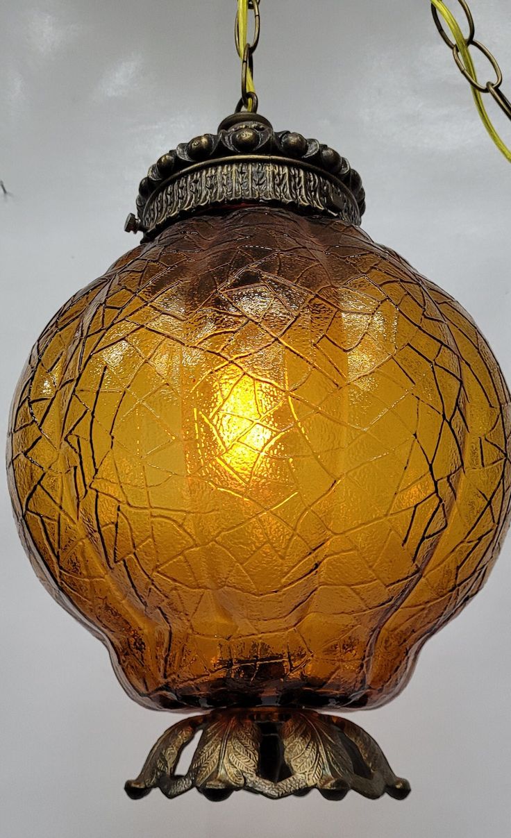 a yellow glass light hanging from a ceiling