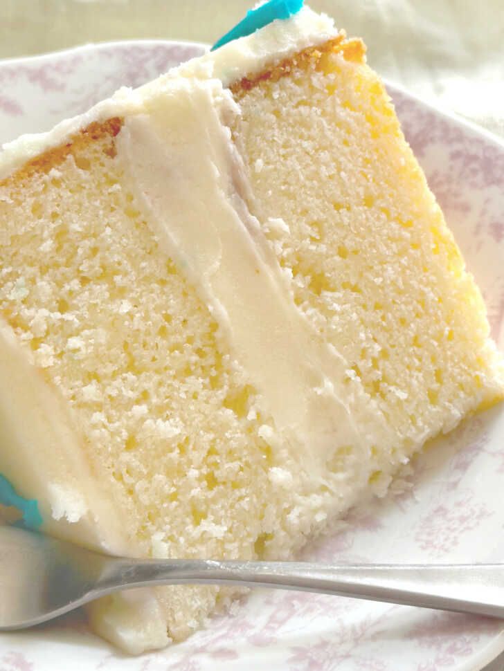 a slice of white cake on a plate with a fork and spoon next to it