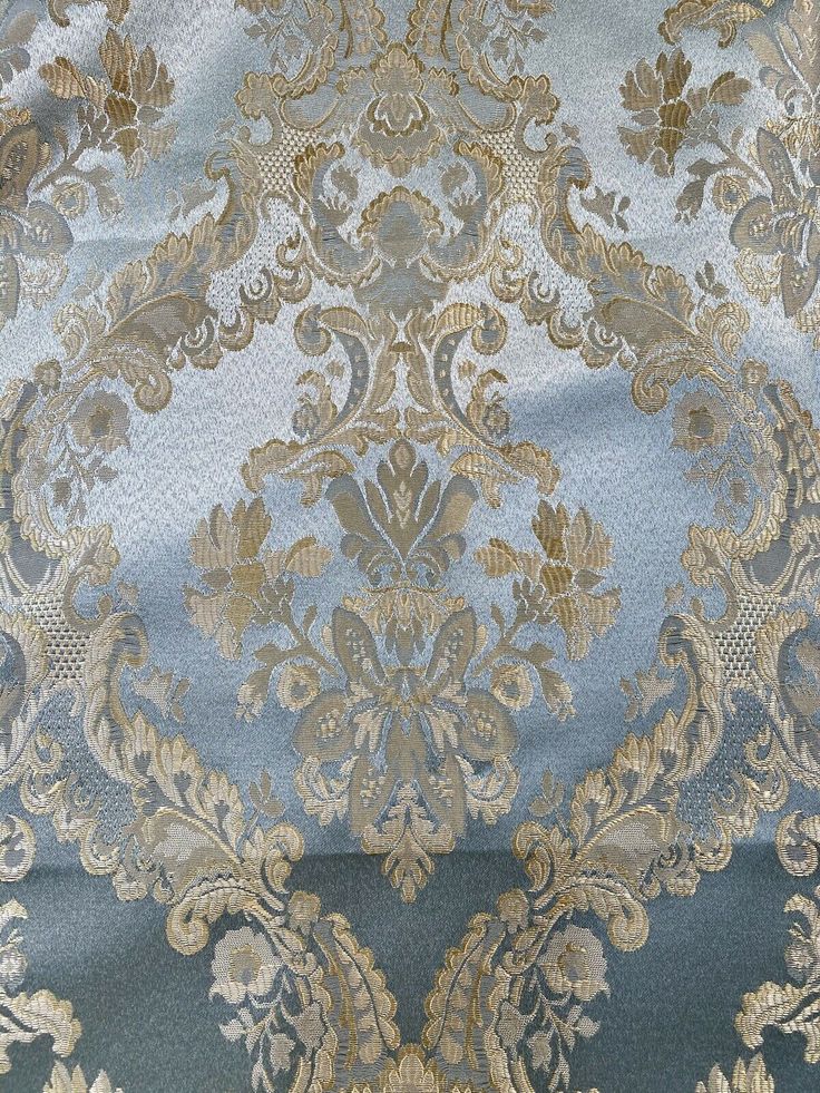 a blue and gold brocaded fabric with an intricate design on the bottom half