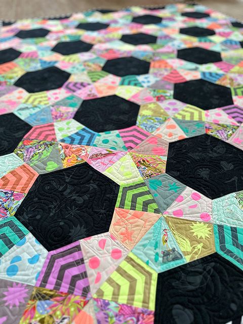 a quilted table top with black and multicolored hexagons on it