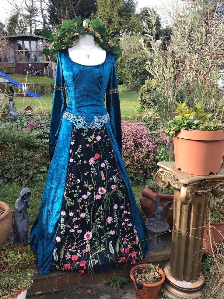 a blue dress with flowers on it sitting in front of a potted planter