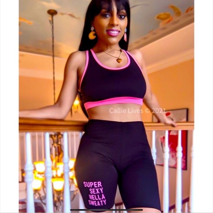 a woman in black and pink sports bra top standing on stairs with her arms out