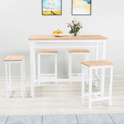 a white table with four stools in front of it and two pictures on the wall