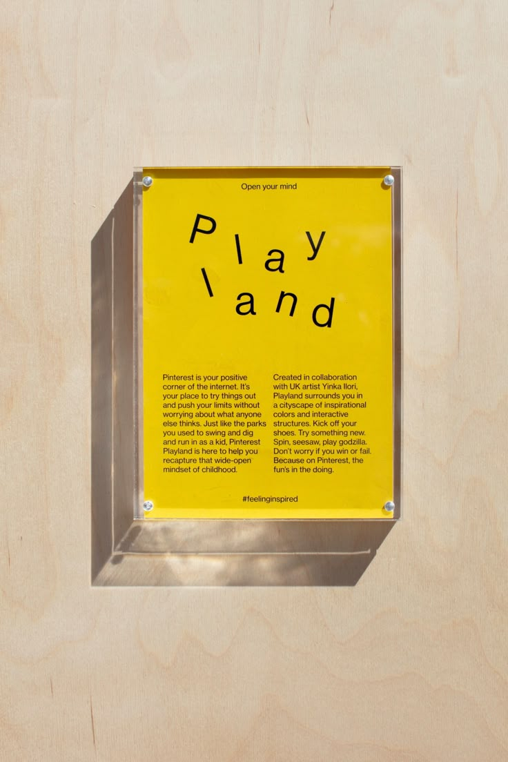 a yellow sign that says play land in front of a wooden wall with metal frame