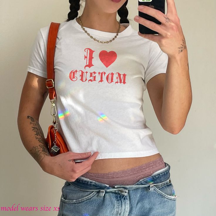 y2k custom text baby tee crop top   your new fave rave shirt  100% cotton ❥this custom tee is a dream! a simple statement piece that is unique to you!      ✺this is a miniaturized t-shirt different from modern crop tops. tee fits true to size, meaning order your typical t-shirt size. for the perfect fit- please see size chart prior to purchase ❣︎Love the vibe, but don't see exactly what you want? Send a message my way! I'd love to create something custom for you❣︎ Shop Policies: ❥ Each item is made to order. Please allow 1-7 business days for the shipping of your product.  ✺ No Returns: Due to our print-on-demand process, we do not accept returns. Please carefully review the sizing chart provided to ensure the perfect fit.  ☺︎ If you have any questions, feel free to reach out ☺︎ Fitted Y2k T-shirt With Text Print, Y2k Cotton Cropped T-shirt With Letter Print, Fitted Y2k T-shirt With Letter Print, Y2k Style Cotton Cropped T-shirt With Short Sleeves, Y2k Style Cropped Cotton T-shirt With Short Sleeves, Y2k Short Sleeve Crop Top With Letter Print, Y2k Style Text Print Crop Top T-shirt, Y2k Style Letter Print Crop Top, Y2k Fitted T-shirt With Custom Print