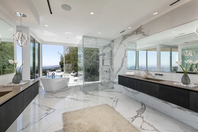 a large bathroom with marble floors and white walls, along with an enormous bathtub