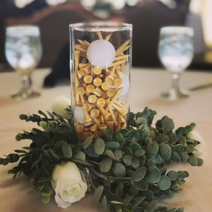 a vase filled with flowers sitting on top of a table next to a golf ball