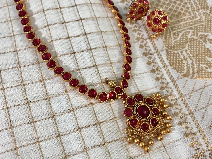 Most sought after & in demand, unique Red (Araku) Kemp Jewelry Short Fancy Necklace set with earrings in gold finish. Necklace measures 10" ( 25.5 cms) long with 1.5" pendant.  It is a Free Size necklace as it comes with an adjustable rope back which measures 12" in length.  Pair it with your gold zari saree blouse for that classic look.  Great for temple wear, wedding guests, party wear, festive wear,  traditional temple jewelry, classic South Indian wear, or as bharatanatyam jewelry & for kids Kemp Necklace Gold, Temple Jewelry Sets With Matching Earrings, Elegant Ruby Jewelry For Puja, Ruby Jewelry Sets For Celebration, Gold Plated Round Temple Necklace For Festive Occasions, Red Gold Plated Temple Jewelry, Festive Gold Temple Necklace With Matching Earrings, Gold Ruby Jewelry For Diwali, Gold Ruby Temple Necklace As Gift