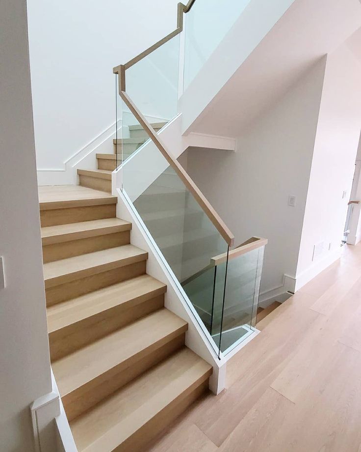 a staircase with glass railing and wooden handrail