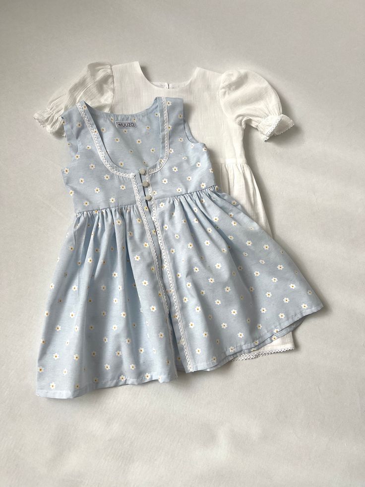 ✿ABOUT THIS DRESS ✓Our handmade set includes a white dress with front knot detail and a soft blue daisy flower-detailed toddler apron look.  ✓The white dress is also lined from the inside, providing extra comfort and durability. ✓The small daisy flower pattern on the apron adds cuteness to the overall look, making your little one look even more adorable.  ✿FABRIC INFORMATION ✓Natural cotton lining 100% under the skirt, cotton, terry cotton fabric. ✓Color of your item may vary slightly from what Cute Cotton Sundress For Daywear, Light Blue Sundress For Spring Garden Party, Light Blue Sundress For Garden Party In Spring, Blue Cottagecore Dress For Spring, Cute Cotton Sundress For Spring, Cute White Sundress For Spring, Light Blue Cotton Sundress For Spring, White Cotton Sundress For Picnic, White Daisy Print Summer Dress