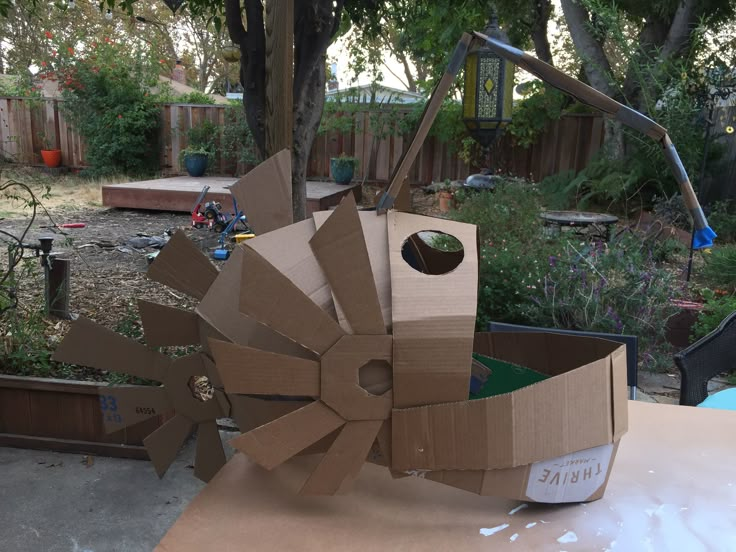 an open cardboard box sitting on top of a table in front of a tree and fence