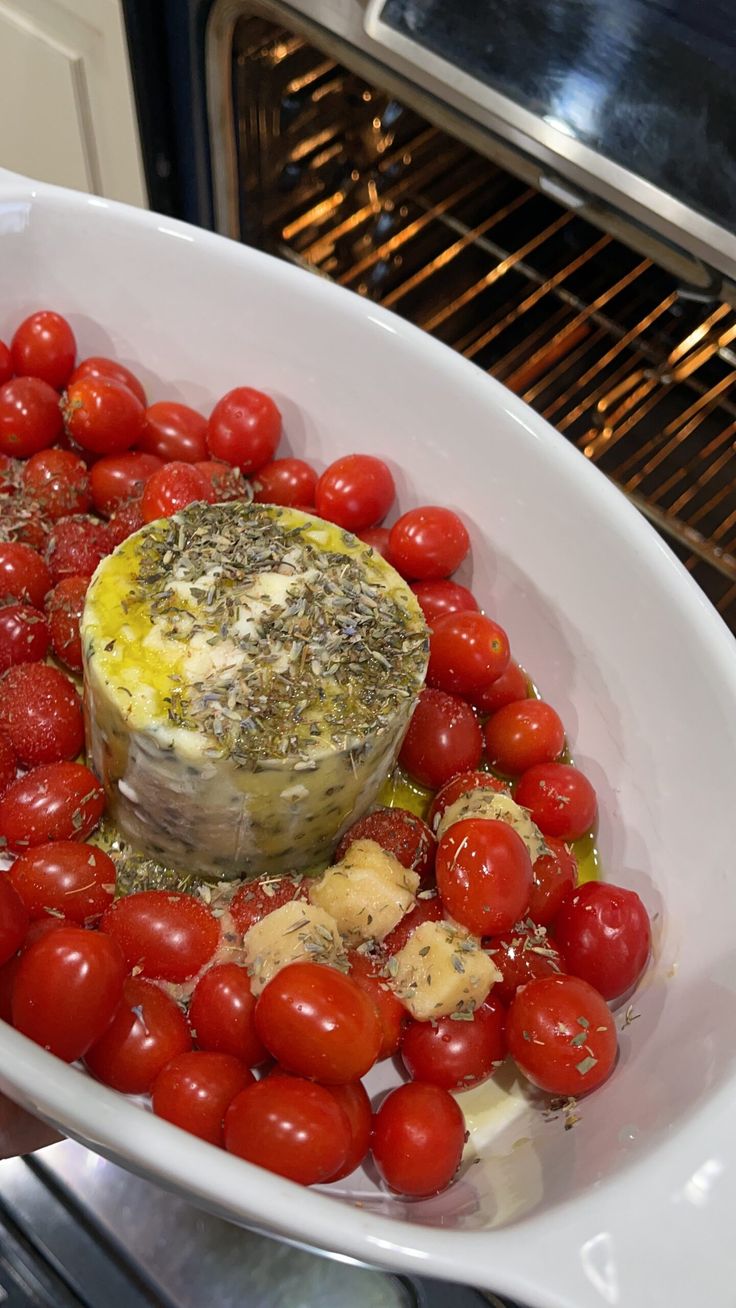 a bowl filled with tomatoes and cheese in front of an oven