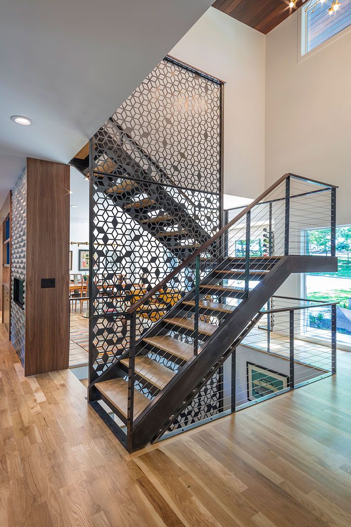 a stair case in the middle of a room with wood flooring and glass railings