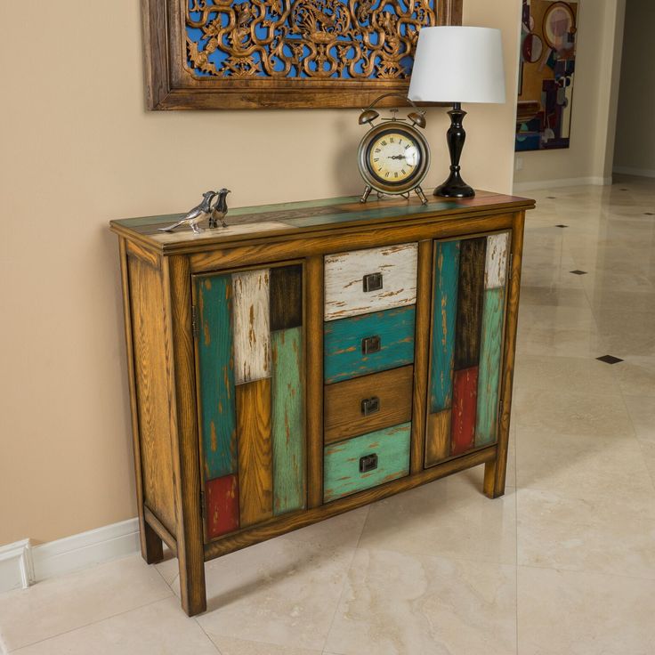 an old dresser has been painted with different colors and designs on the drawers, along with a clock