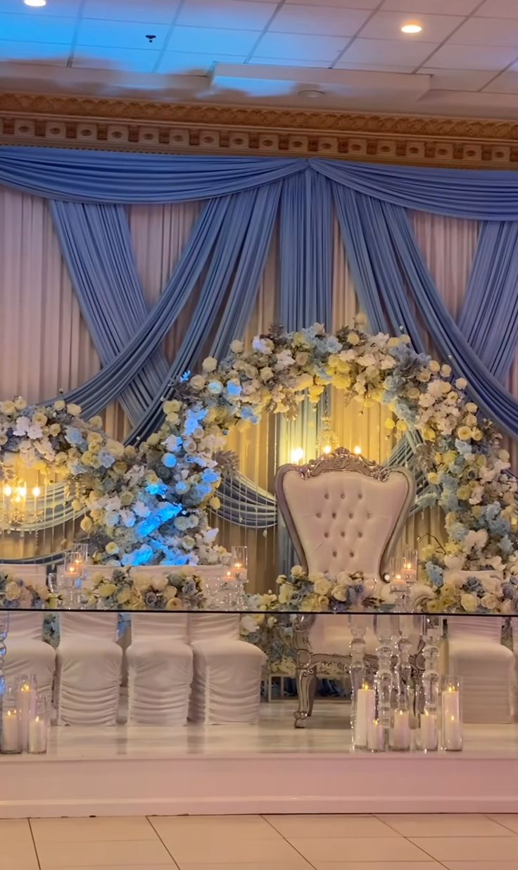 an elaborately decorated table with chairs and flowers on the wall, along with candles