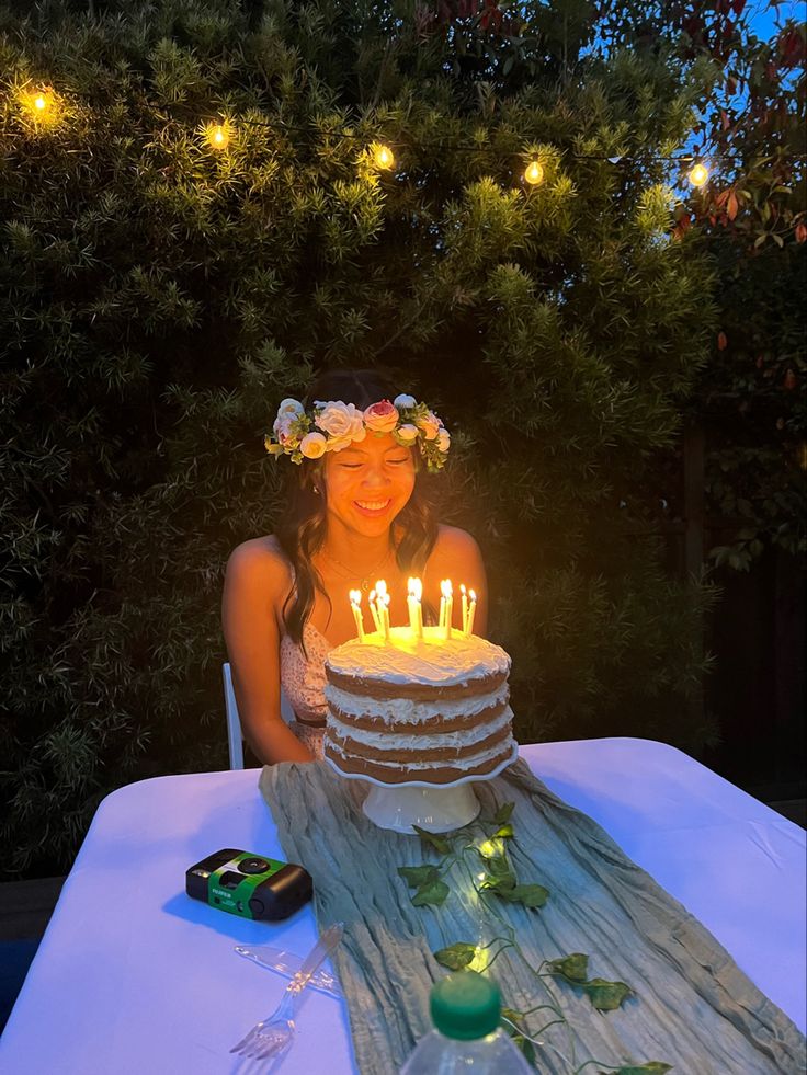 a woman sitting in front of a cake with lit candles