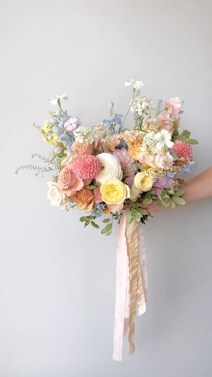 a woman holding a bouquet of flowers in her hand on a gray background with white and pink colors