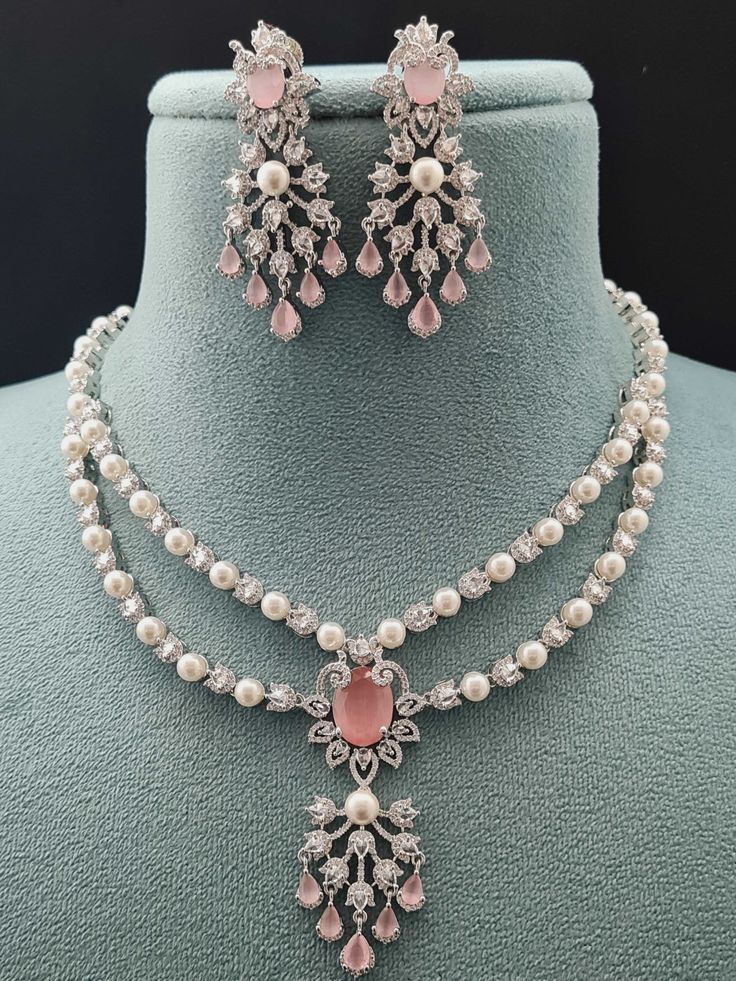 Step into elegance with our 2 Layer Pendant AD Necklace Set, part of our Luxe Royal Heritage collection, a stunning fusion of luxury and grace. Crafted meticulously, this necklace set captures the essence of American chic and Indian artistry. The soft hues of pink and radiant gold intertwine seamlessly, offering a touch of opulence to any ensemble. Lightweight and refined, they embody sophistication and cross-cultural allure, making every moment a statement of timeless beauty. Handcrafted Metal: Luxury White Kundan Necklace With Intricate Design, Luxury Gold Fusion Jewelry Sets, Luxury Pink Jewelry For Wedding, Exquisite Pink Jewelry For Party, Luxury Pink Pearl Necklace For Wedding, Luxury Pink Necklace For Party, Luxury Pink Pearl Necklace, Hand Set Pink Jewelry Sets For Reception, Pink Hand-set Jewelry Sets For Reception