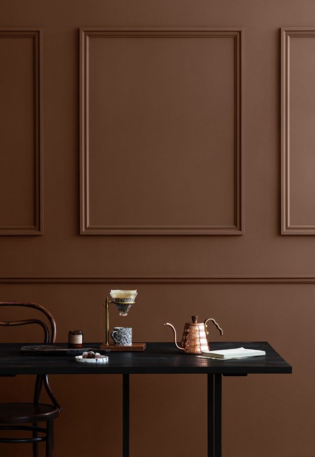 a table with a tea pot, cup and saucer on it in front of brown paneled walls