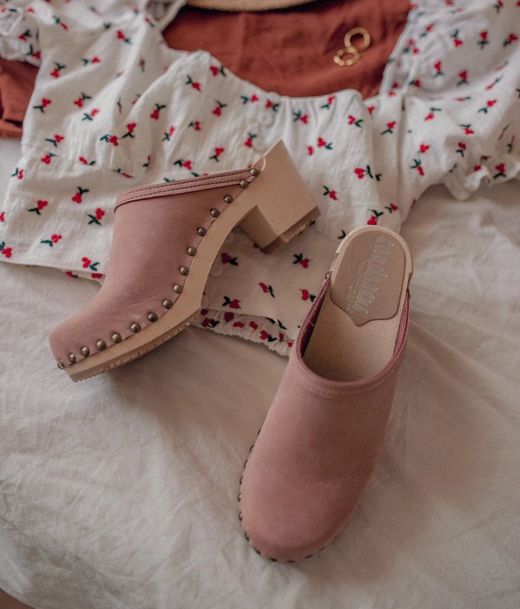 Made by skilled artisans in Sweden, these blush pink nubuck clog mules feature a high heel and eye-catching stud detailing on the sides. From date nights to ladies' nights out, Rome delivers unparalleled style and confidence. Clog measurements:Heel height: 2 5/8” (6.5 cm)Toe height:﻿ 1 1/2″ (3.8 cm) Fit:NarrowLeather:Nubuck leatherClogs consist of:Base: European Lime Wood Sole: Rubber sole Fastening: Brass studs Spring Slip-on Clogs With Studded Rubber Outsoles, Spring High Heel Clogs With Studded Rubber Outsoles, Chic Suede Clogs With Wooden Heel, Spring Suede Clogs With Block Heel, Pink Mules With Wooden Heel For Spring, Spring Pink Mules With Wooden Heel, Suede Open Heel Clogs For Spring, Pink Mules With Wooden High Heel, Pink High Heel Mules With Wooden Heel