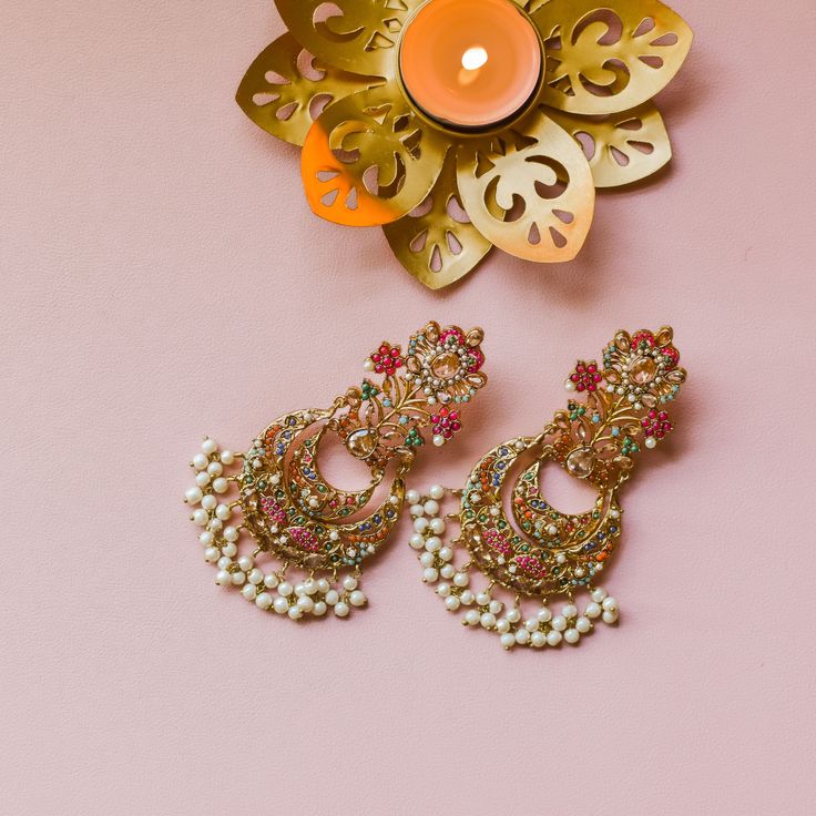 Nauratan timelessness that carry distinct style, intricacy and craftsmanship of a bygone era! A talismanic pair studded with ethereal stones and the grace of pearl moti along with the radiance of traditional and aesthetic identity. Approximate earrings length is 4". Gold-plated on high-quality brass as base metal. Made by order. Kindly allow 5-7 weeks for the delivery of this item. For custom or urgent requests, please contact support@alacouture.com. *Please Note: The multi-colored beadwork migh Elegant Bridal Earrings For Wedding And Navratri, Elegant Chandbalis For Navratri Festive, Elegant Navratri Festive Chandbalis, Elegant Festive Chandbalis For Navratri, Temple Jewelry Stone Work Danglers For Celebration, Temple Jewelry Danglers With Stone Work For Celebration, Fusion Style Pearl Drop Chandelier Earrings For Celebration, Fusion Style Chandelier Earrings With Pearl Drop For Celebration, Elegant Pearl Earrings With Stone Work As Gift