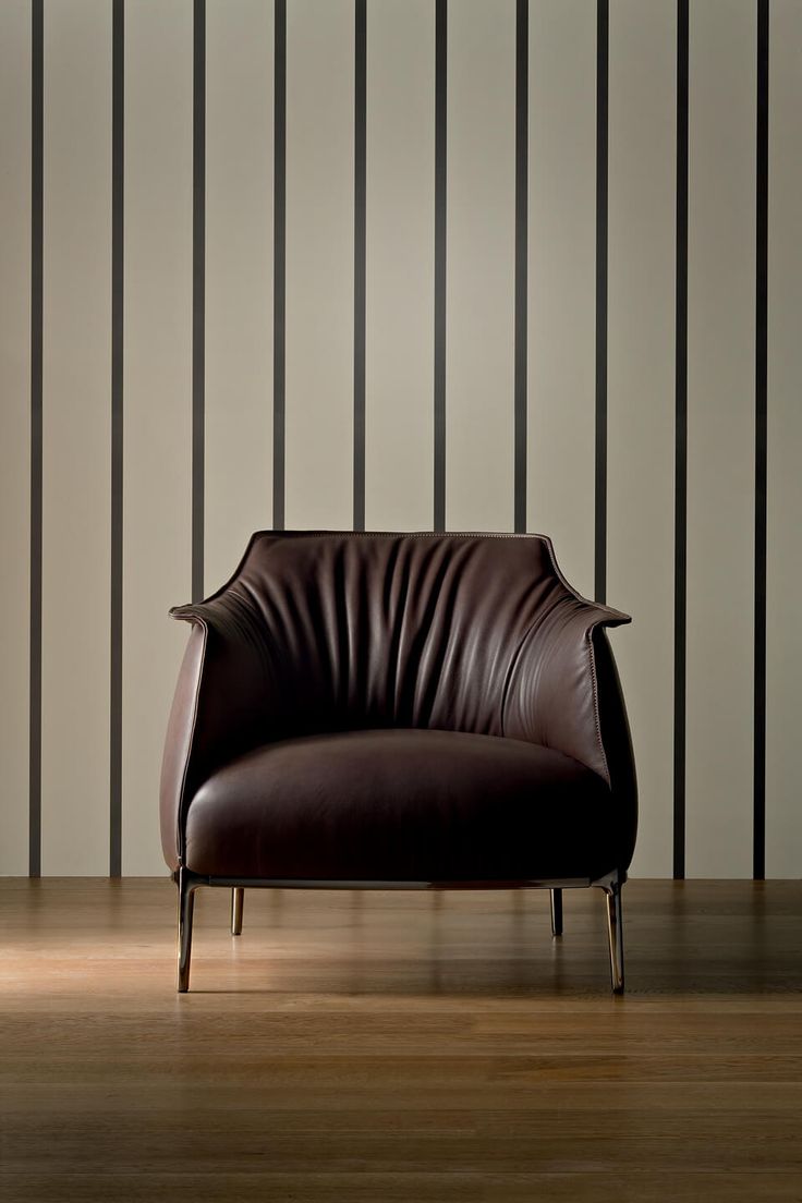 a brown leather chair sitting on top of a hard wood floor next to a wall