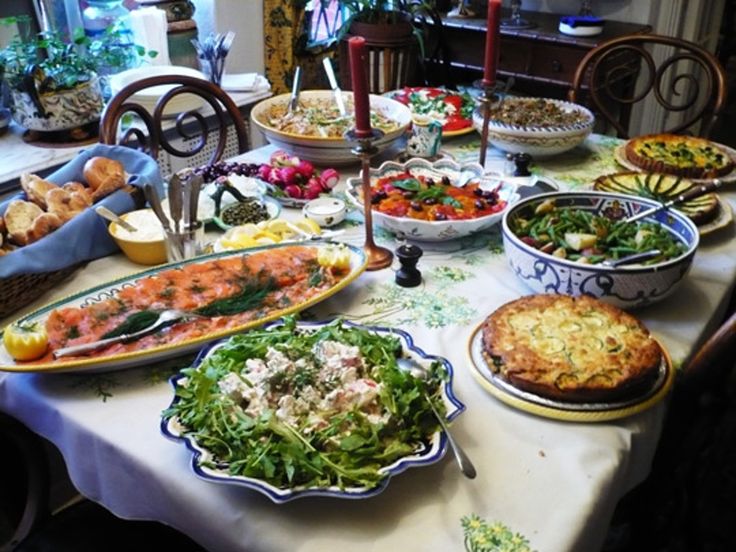 a table filled with lots of food on top of a white table cloth covered table