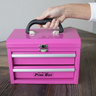 a pink box with two drawers and a hand holding the handle on it's top